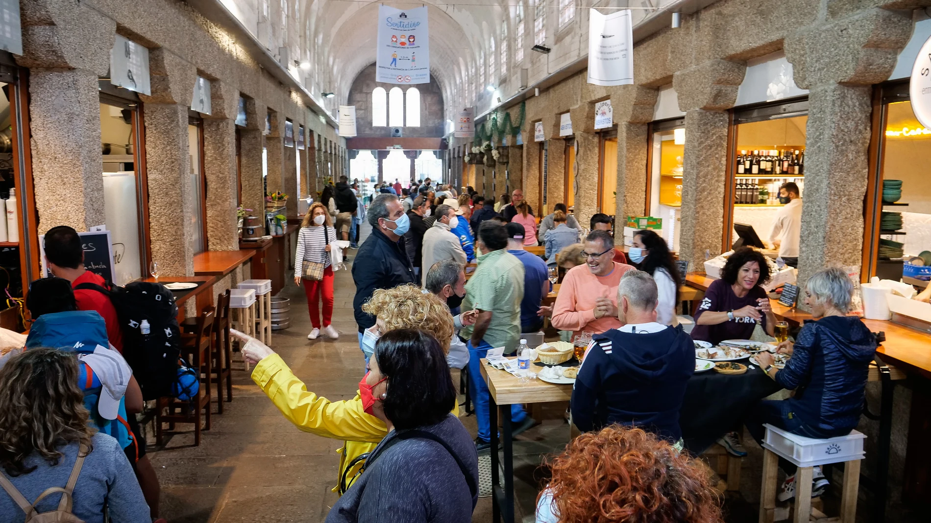 Varias personas acuden a un espacio con locales de hostelería en Santiago de Compostela, A Coruña (Galicia)