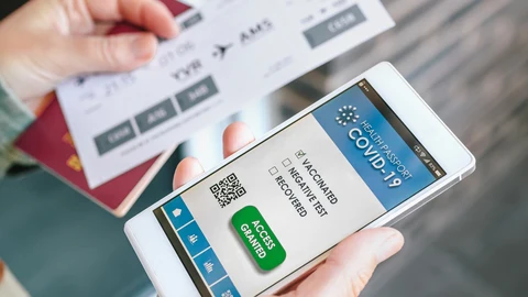 Una mujer sostiene su teléfono con el certificado del pasaporte covid y la tarjeta de embarque