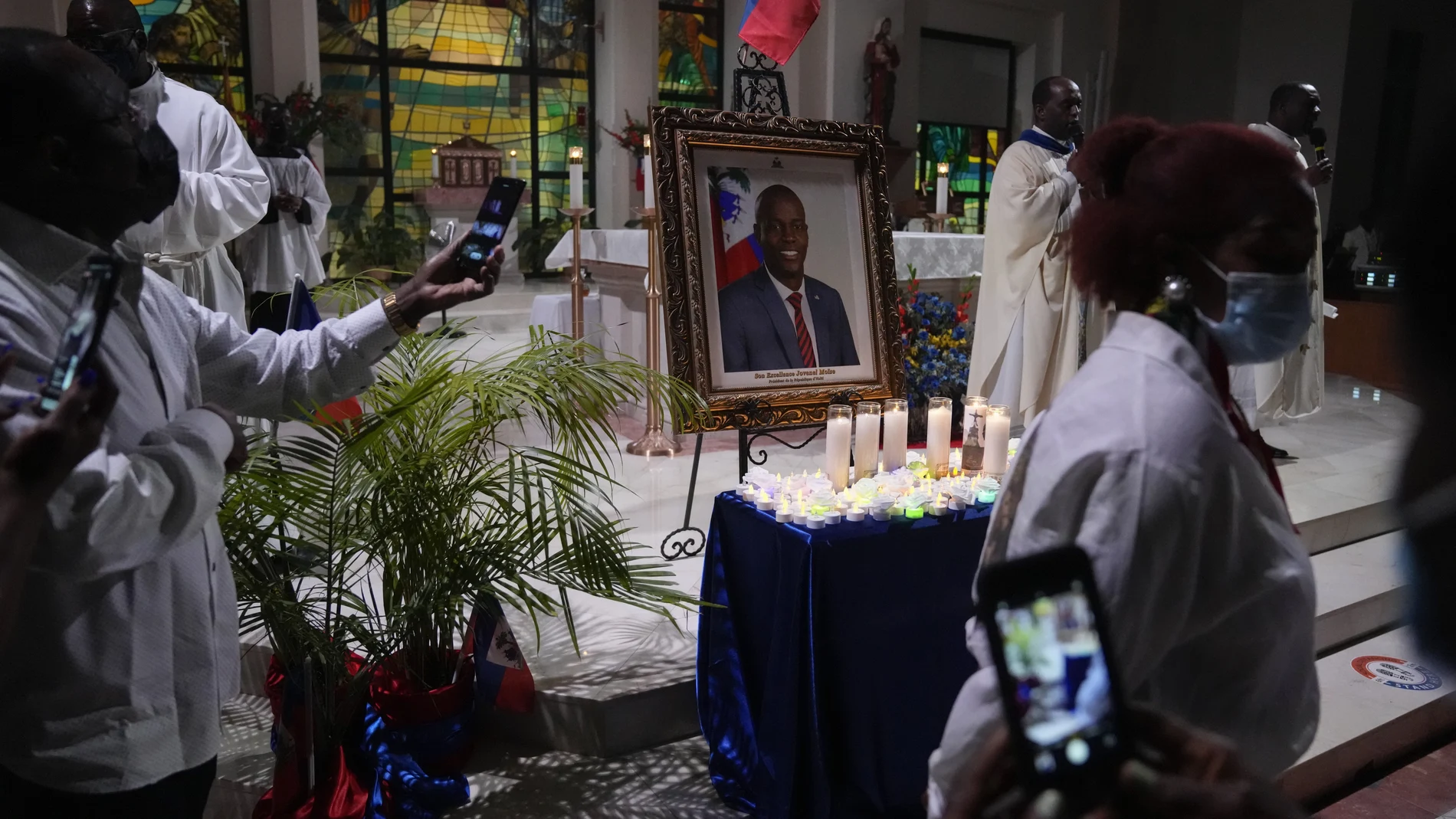 Mourners take pictures of electric candles resting in front of a portrait of Haiti's assassinated President Jovenel MoÃ¯se, during a memorial service at Notre Dame d'Haiti Catholic Church on Thursday, July 22, 2021, in the Little Haiti neighborhood of Miami. Miami's Haitian Consul General hosted the service for members of the city's large Haitian community to pray for the troubled nation and pay their respects to the president, who was slain in a July 7 attack at his home which left his wife seriously wounded. (AP Photo/Rebecca Blackwell)