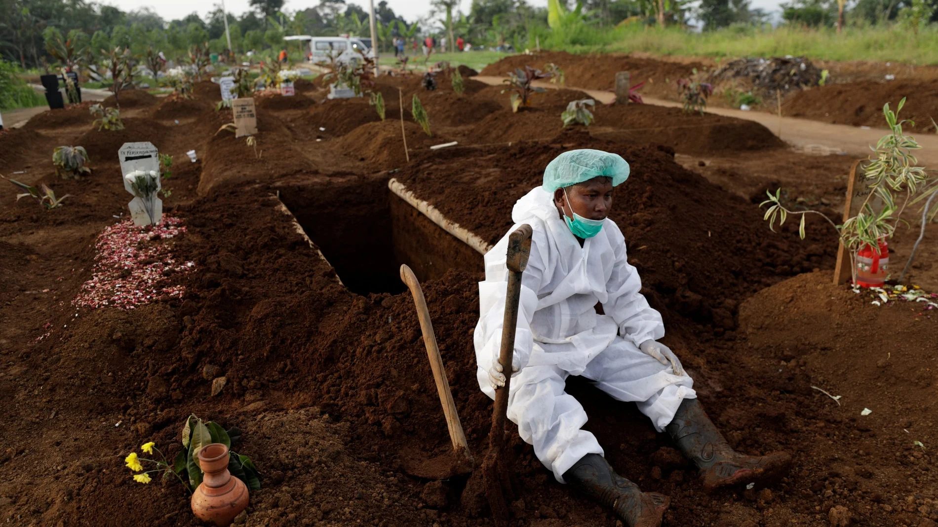 FILE PHOTO: A gravedigger wearing personal protective equipment rests after the burial of 64-year-old Yoyoh Sa'diah who passed away due to complications related to COVID-19 whilst isolating at her home in Bogor, West Java province, Indonesia, July 8, 2021. REUTERS/Willy Kurniawan/File Photo