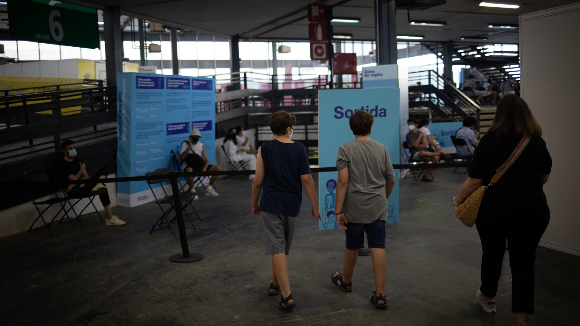 Dos adolescentes acuden a recibir la vacuna contra la covid-19 en el recinto de Montjuïc de Fira de Barcelona. David Zorrakino / Europa Press