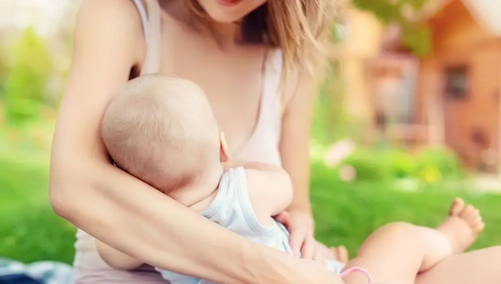 Una mujer da el pecho a su bebé en un parque