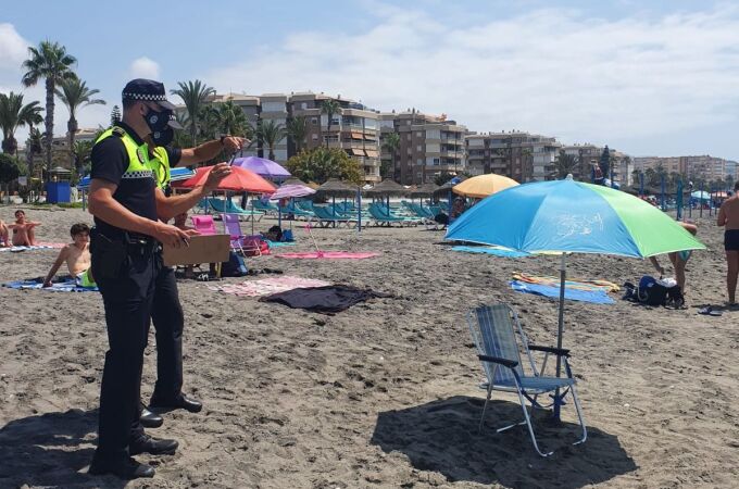 Dos policías locales vigilan una sombrilla vacía en la playa de Torrox