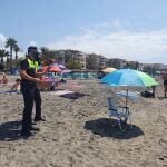 Dos policías locales vigilan una sombrilla vacía en la playa de Torrox
