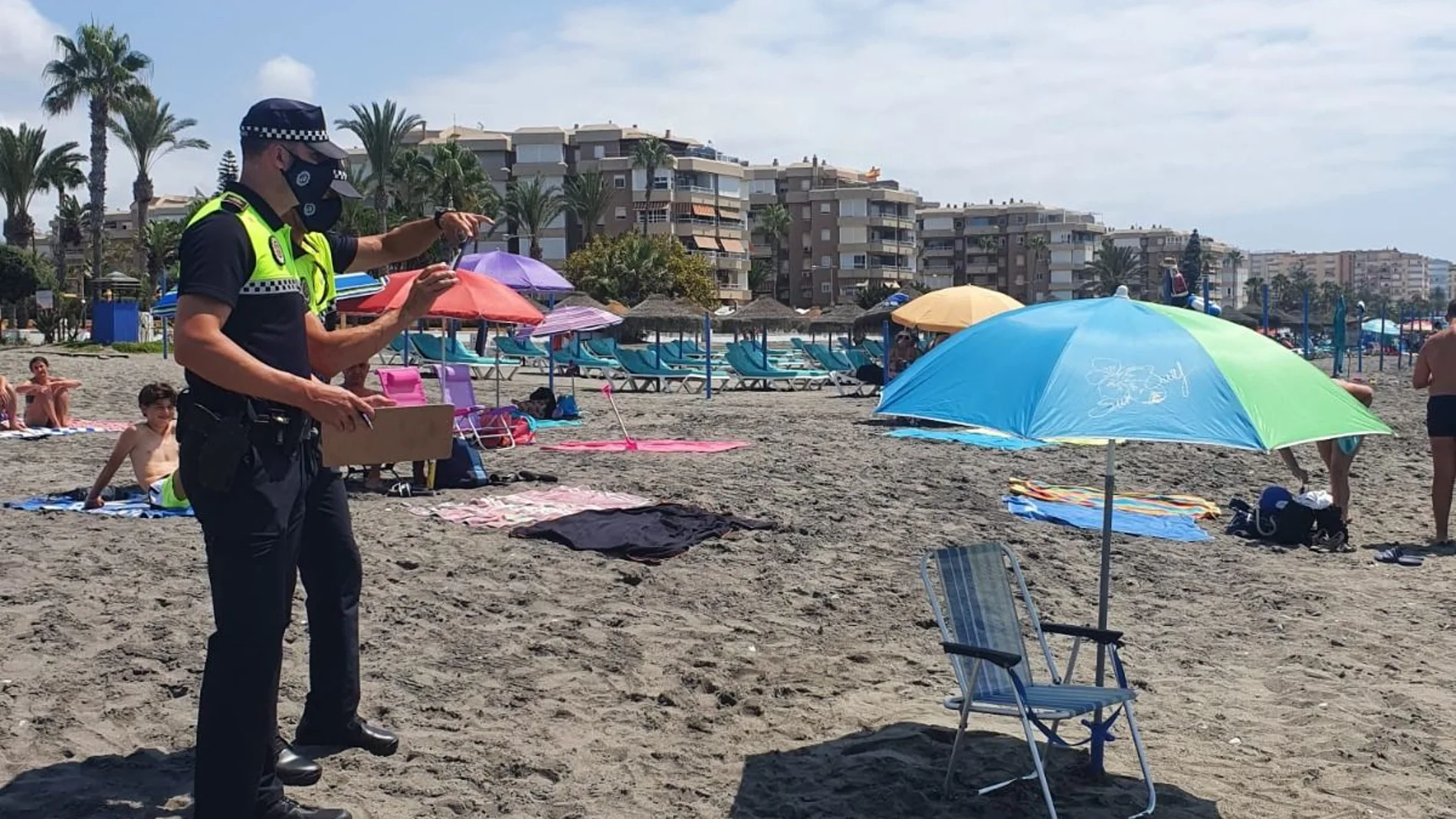 Dos policías locales vigilan una sombrilla vacía en la playa de Torrox