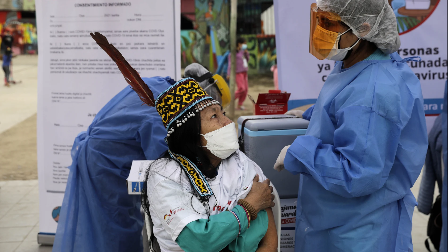 A Shipibo-Konibo Indigenous woman talks to a nurse after receiving the first dose of the Sinopharm COVID-19 vaccine in the Cantagallo neighborhood of Lima, Peru, Monday, Aug. 9, 2021. (AP Photo/Guadalupe Pardo)