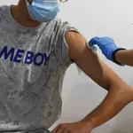 Un adolescente recibe la primera dosis de la vacuna Pfizer en el punto de vacunación de Xátiva, situado en el Hogar de los Jubilados