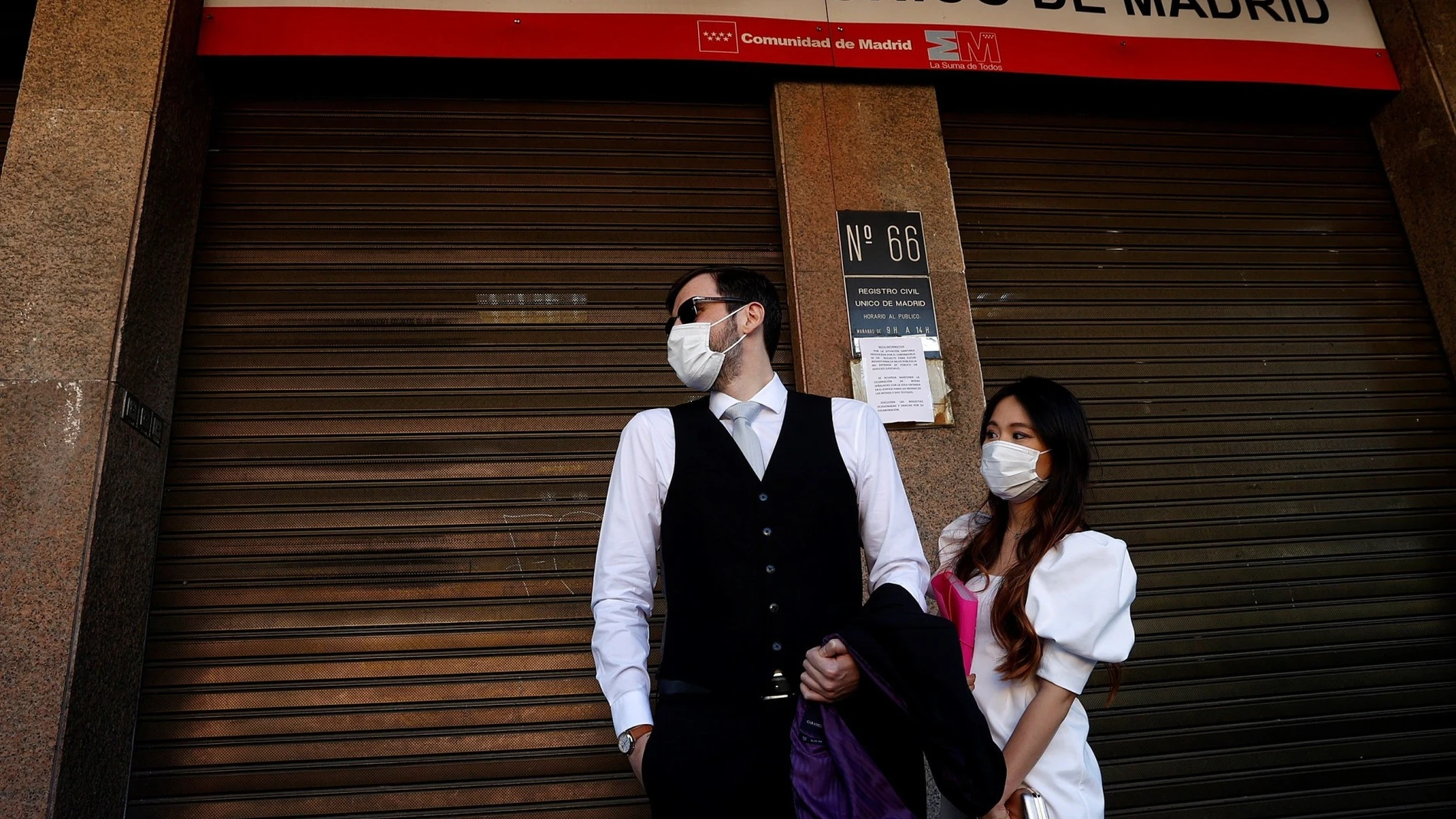 Rafael y Miki, protegidos con mascarillas, esperan para contraer matrimonio a las puertas del Registro Civil de Madrid. A 11 de agosto de 2021