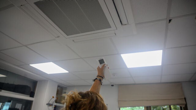 Una mujer enciende el aire acondicionado en una oficina