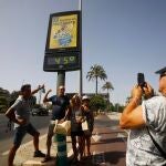 Unos turistas se fotografían debajo de un termómetro de calle que marca 45 grados en Córdoba