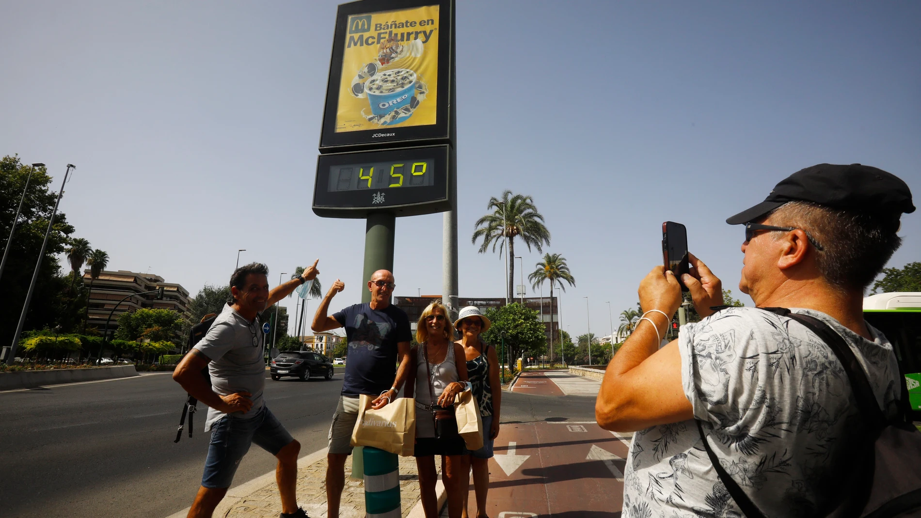 Unos turistas se fotografían debajo de un termómetro de calle que marca 45 grados en Córdoba