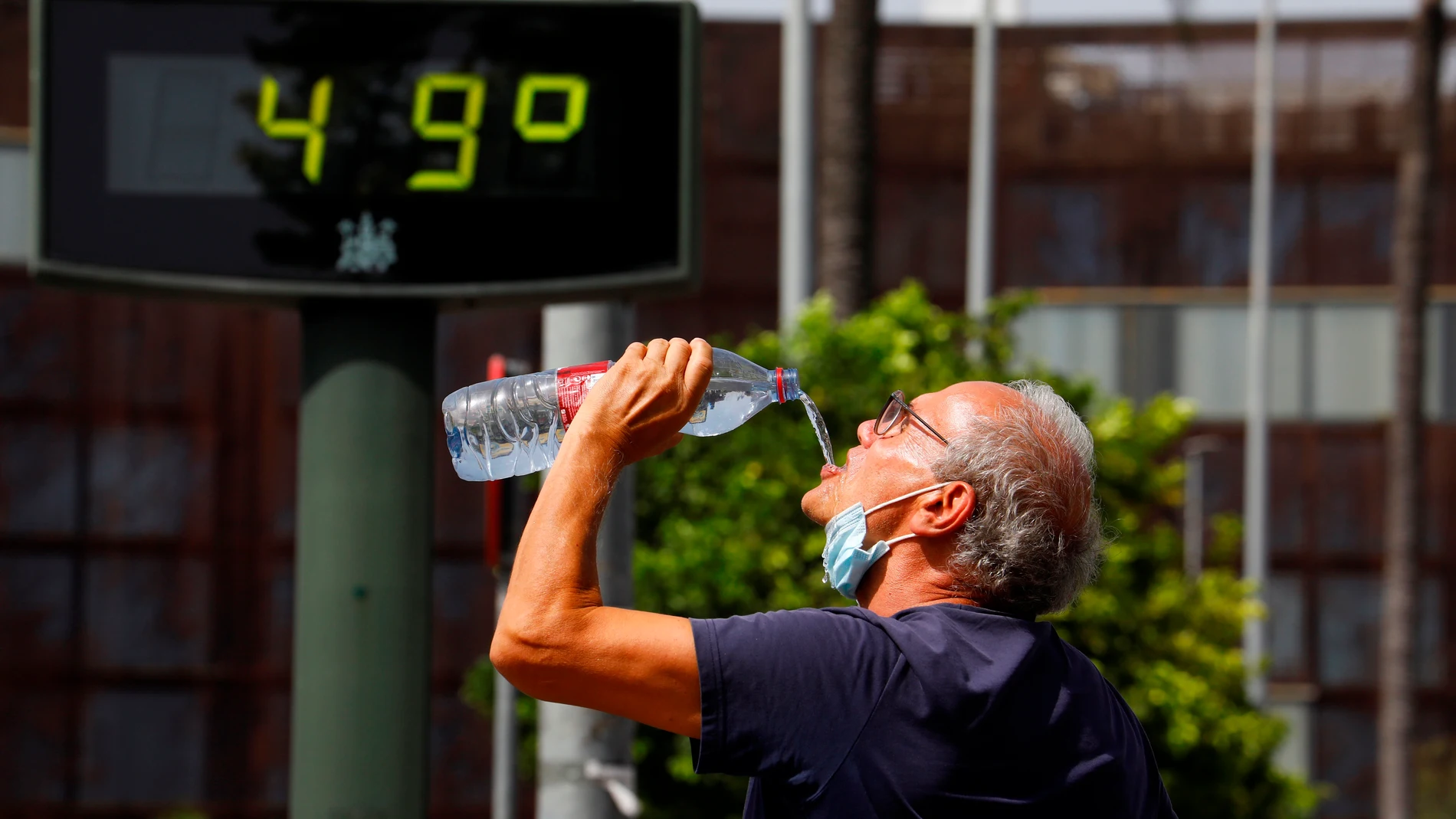 Un turista se refresca en el centro de Córdoba junto a un termómetro que, recalentado por su exposición al sol, marca 49 grados