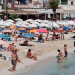 Varios bañistas disfrutan de una soleada jornada en la playa de Punta Prima de Menorca