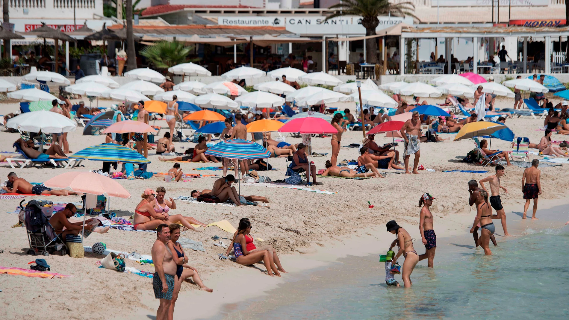 Varios bañistas disfrutan de una soleada jornada en la playa de Punta Prima de Menorca