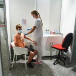 Una sanitaria vacuna a un adolescente con la primera dosis de la vacuna Moderna en la Ciudad de las Artes de Valencia