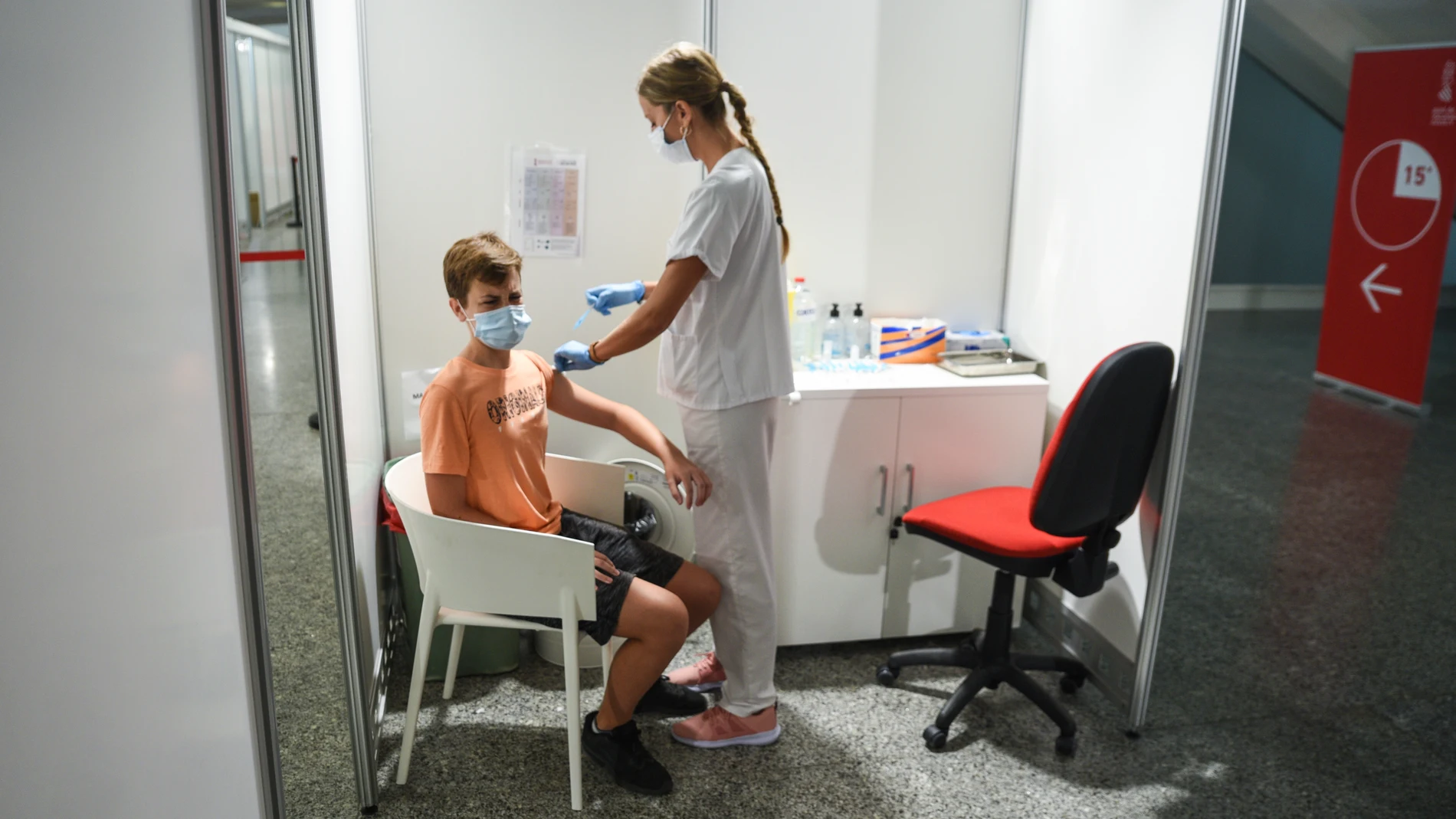 Una sanitaria vacuna a un adolescente con la primera dosis de la vacuna Moderna en la Ciudad de las Artes de Valencia