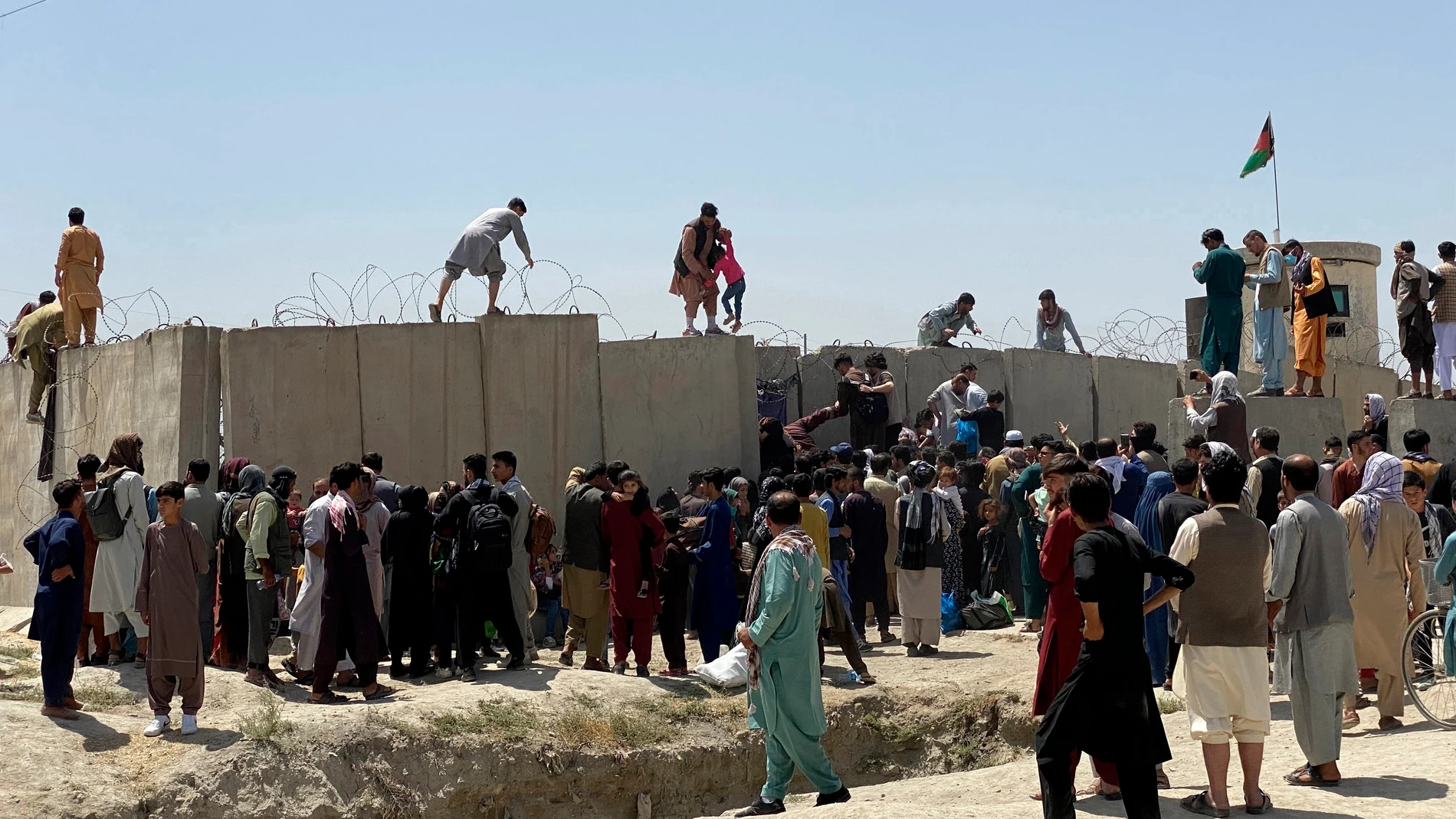 Afganos se agolpan a lo largo del muro del aeropuerto internacional Hamid Karzai antes de saltarlo en un intento de abandonar el país. EFE/STRINGER