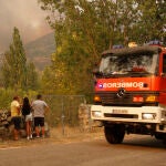 Un camión de bomberos pasa por delante de tres vecinos durante el incendio en el término abulense de Navalacruz