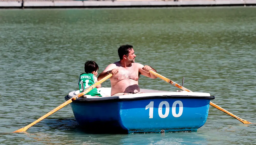 Un hombre y un niño disfrutan de un paseo en barca en el lago del Parque del Retiro de Madrid.