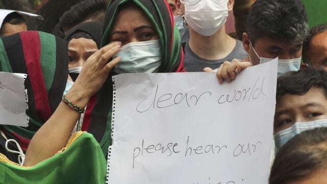An Afghan woman weeps as she holds a poster during a rally outside the building that houses UNHCR representative office in Jakarta, Indonesia, Tuesday, Aug. 24, 2021. Hundreds of Afghan refugees living in Indonesia, mostly members of the Hazara ethnic minority, held the rally on Tuesday decrying the Taliban's takeover of their country and calling for resettlement in third countries. (AP Photo/Tatan Syuflana)