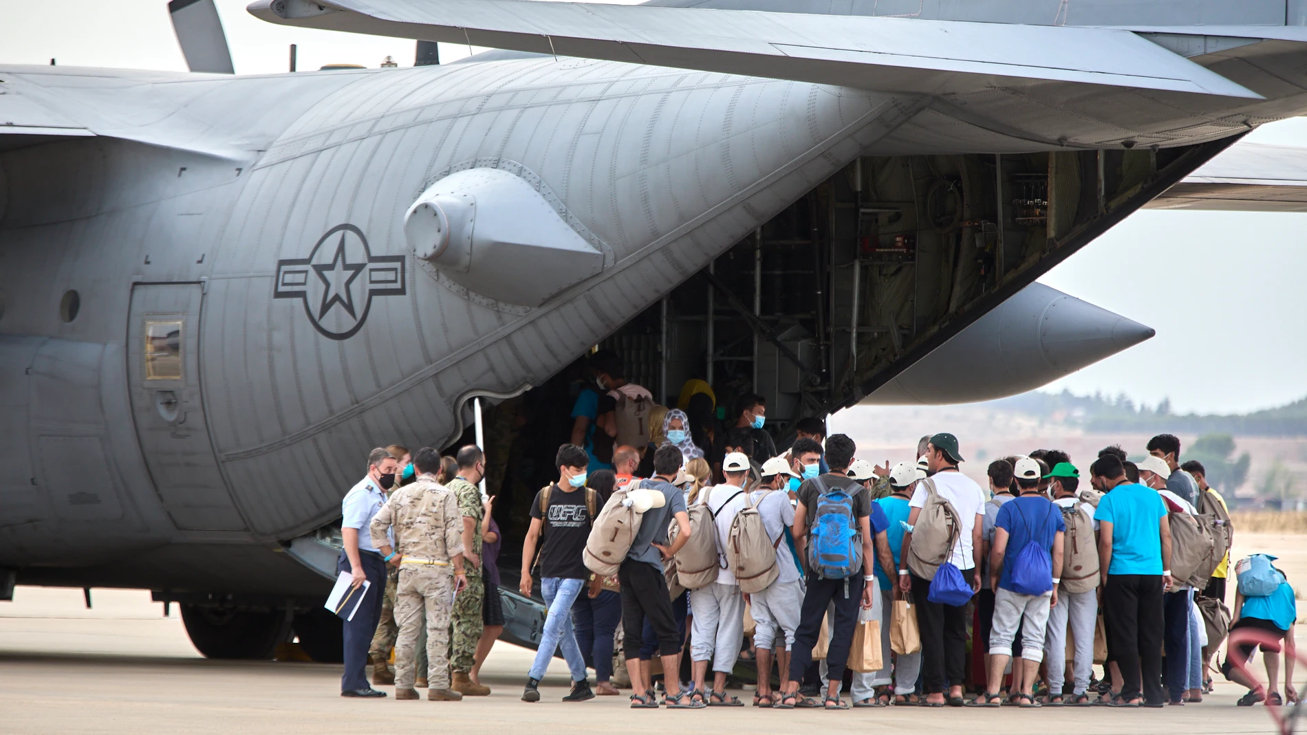 Un grupo de jóvenes y familias afganas, se dirigen a subir a un avión estadounidense para ser trasladados a Alemania