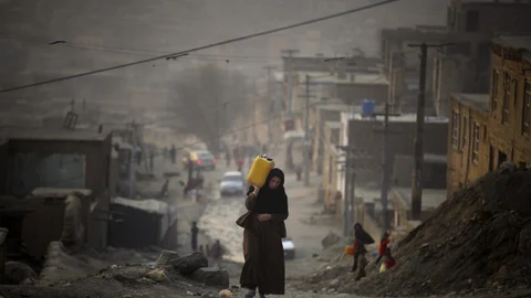 ADVANCE FOR PUBLICATION ON FRIDAY, SEPT. 3, AND THEREAFTER - FILE - In this Monday, Dec. 27, 2010 file photo, a woman carries water in a plastic container as she ascends a slope on the way towards her home in Kabul, Afghanistan. (AP Photo/Altaf Qadri, File)