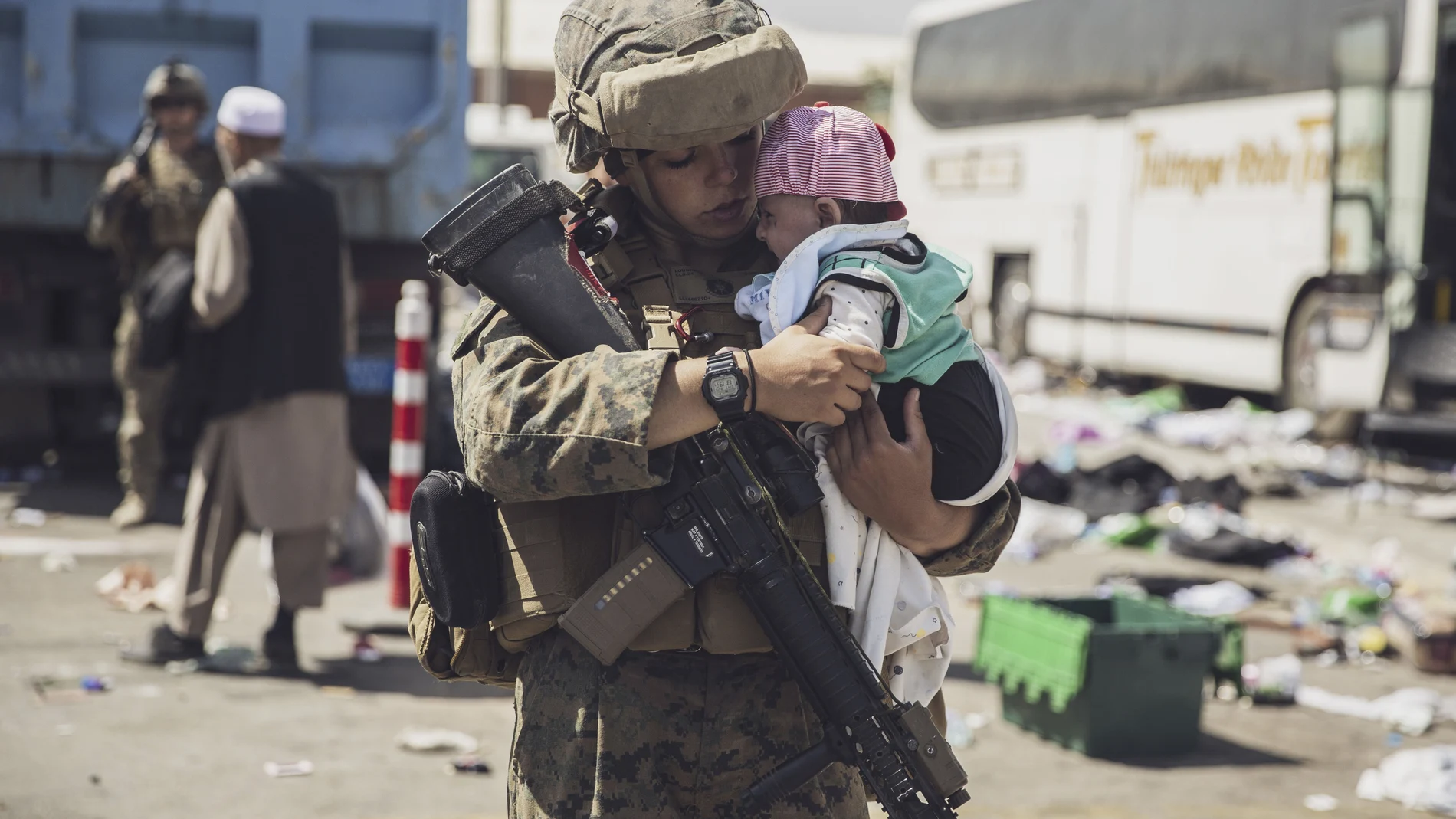 In this image provided by the U.S. Marine Corps, a Marine with the 24th Marine Expeditionary Unit (MEU) carries a baby as the family processes through the evacuation control center at Hamid Karzai International Airport in Kabul, Afghanistan, Saturday, Aug. 28, 2021. (Staff Sgt. Victor Mancilla/U.S. Marine Corps via AP)