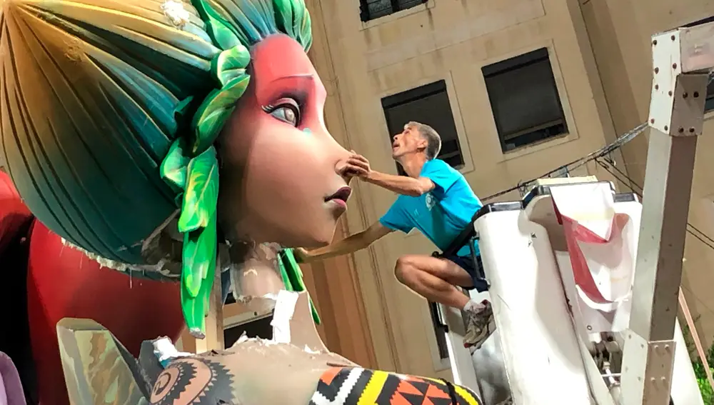 Un artista fallero coloca la cabeza del remate de la falla de la sección especial Sueca Literato Azorín que se desplomó tras la gran tromba de agua que descargó en Valencia el pasado lunes