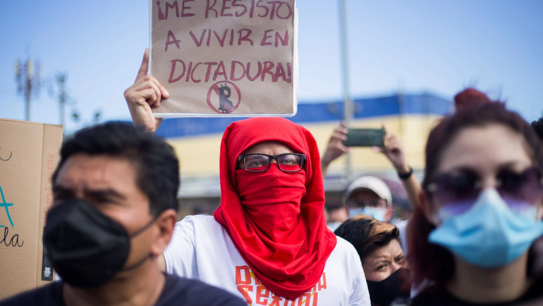 A demonstrator holds up a banner that reads "I resist living in a dictatorship" during a protest against El Salvador's President Nayib Bukele and the recent decision by the Constitutional Chamber of the Supreme Court of Justice approving a law that allows his re-election in 2024, in San Salvador, El Salvador September 5, 2021. REUTERS/Victor Pena