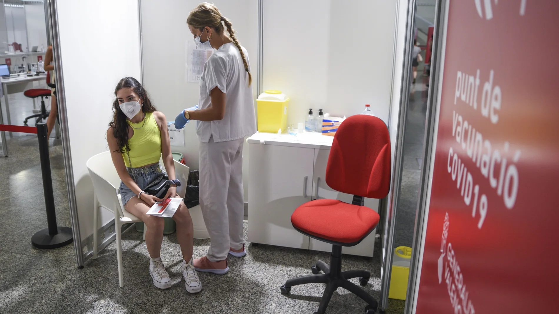 Una sanitaria vacuna a una adolescente con la primera dosis de la vacuna Moderna en la Ciudad de las Artes