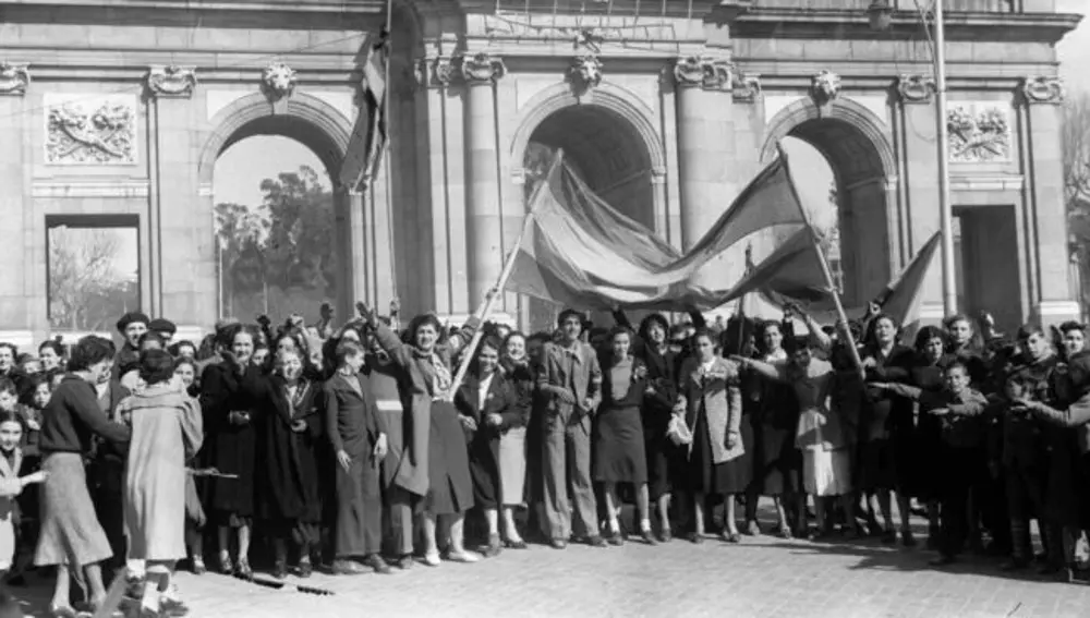 Fernández Flórez vivió en primera persona el terror de los días bélicos de Madrid. En la imagen, frente a la Puerta de Alcalá, un grupo de madrileños con una bandera nacional, espera la llegada de las tropas de Franco.
