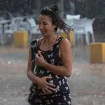 Una mujer corre bajo la lluvia en Sevilla