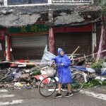 A person pushes a bicycle past damaged buildings, following an earthquake in Luzhou city of southwestern province of Sichuan, China September 16, 2021. cnsphoto/via REUTERS ATTENTION EDITORS - THIS IMAGE WAS PROVIDED BY A THIRD PARTY. CHINA OUT.