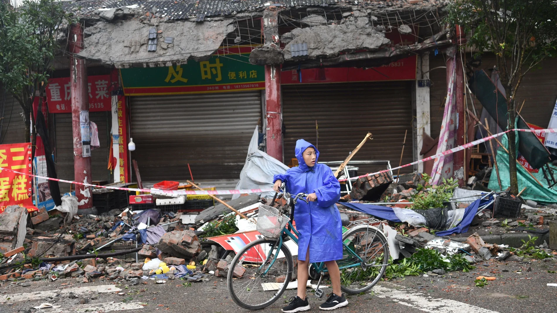 A person pushes a bicycle past damaged buildings, following an earthquake in Luzhou city of southwestern province of Sichuan, China September 16, 2021. cnsphoto/via REUTERS ATTENTION EDITORS - THIS IMAGE WAS PROVIDED BY A THIRD PARTY. CHINA OUT.