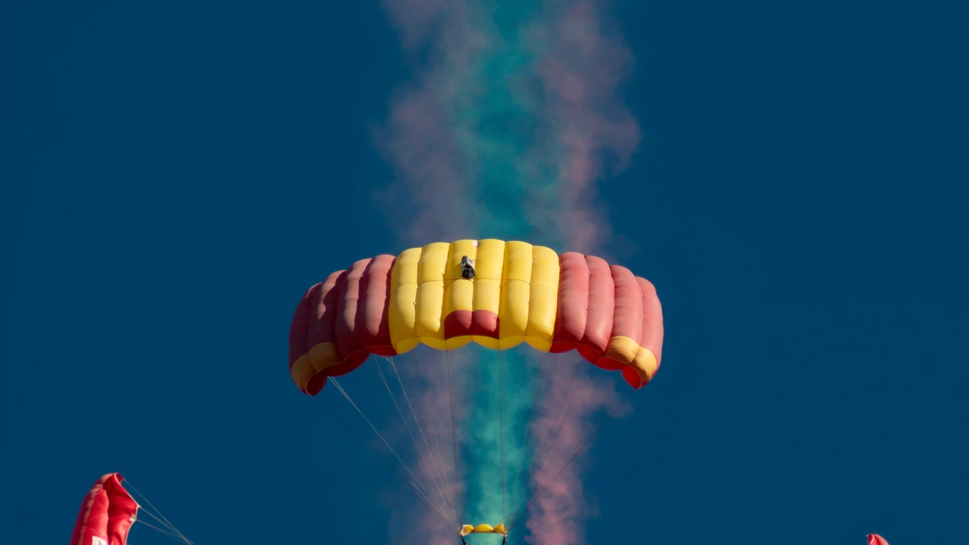 Paracaidistas sobrevuelan el Aeródromo militar de Tablada durante la exhibición aeronáutica