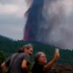 Varias personas observan la actividad de la erupción volcánica, este lunes por la tarde en La Palma