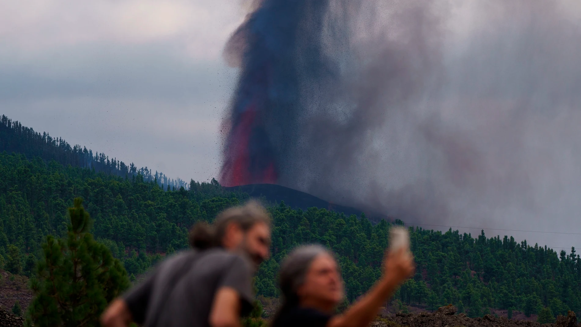 Varias personas observan la actividad de la erupción volcánica, este lunes por la tarde en La Palma