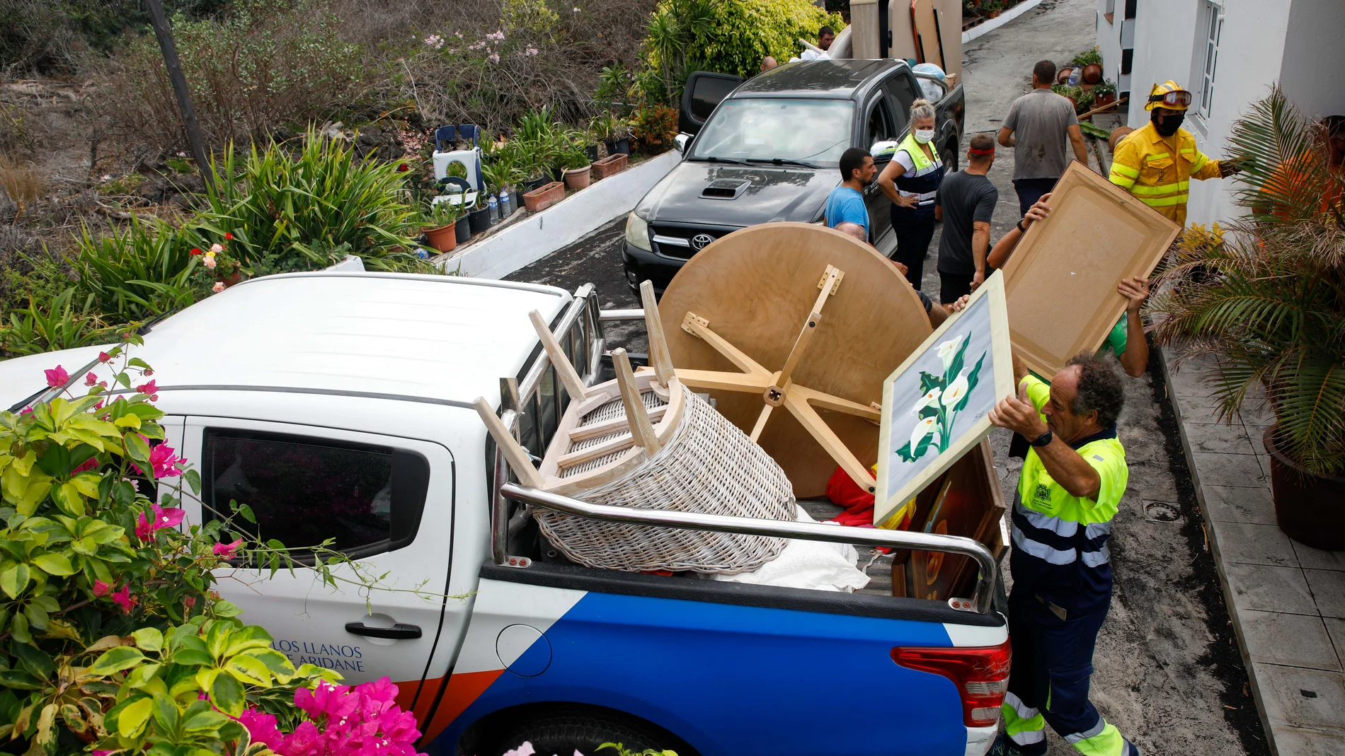 Varias personas de mantenimiento del Ayuntamiento y bomberos colaboran en recoger las pertenencias de los vecinos del núcleo urbano de Todoque durante el desalojo de sus viviendas