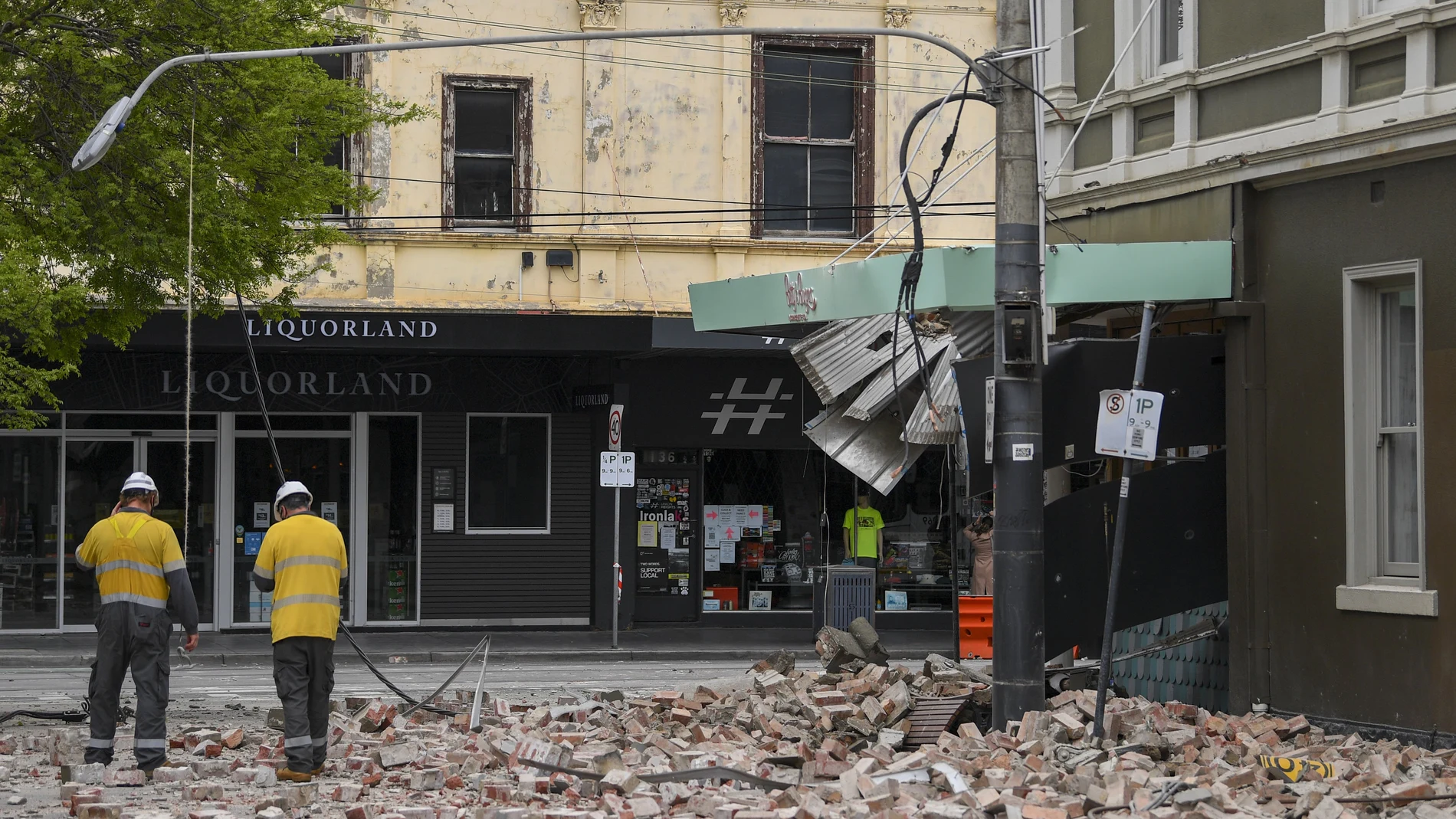 Emergency workers survey damage in Melbourne, Australia, where debris is scattered on a road after part of a wall fell from a building during an earthquake, Wednesday, Sept. 22, 2021. A strong earthquake caused damage in the city of Melbourne in an unusually powerful temblor for Australia, Geoscience Australia said. (James Ross/AAP Image via AP)
