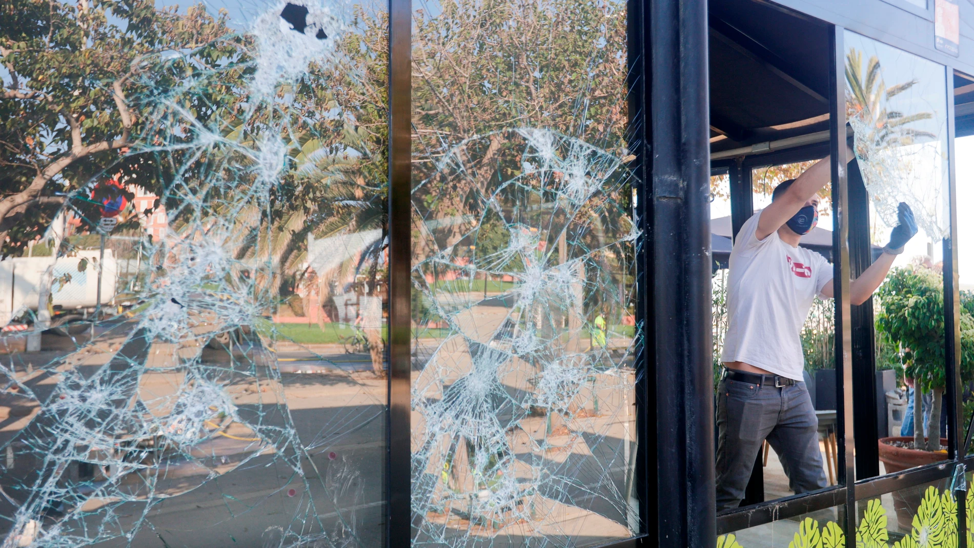El propietario de uno de los locales afectados retira una cristalera tras los incidentes registrados la pasada noche a raíz de un botellón en las playas de Barcelona que se han saldado, según un balance provisional, con 30 detenciones y 39 heridos, han informado fuentes de la Policía de la Generalitat y del Sistema de Emergencias Médicas (SEM). EFE/Quique García