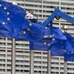 A worker on a lift adjusts the EU flags in front of EU headquarters in Brussels.