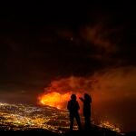 Dos jóvenes contemplan desde el valle de Aridane, en La Palma, la erupción en Cumbre Vieja al anochecer