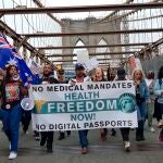 Decenas de activistas y personas antivacunas caminan durante una marcha antivacunas, en el puente de Brooklyn, Nueva York (EEUU).