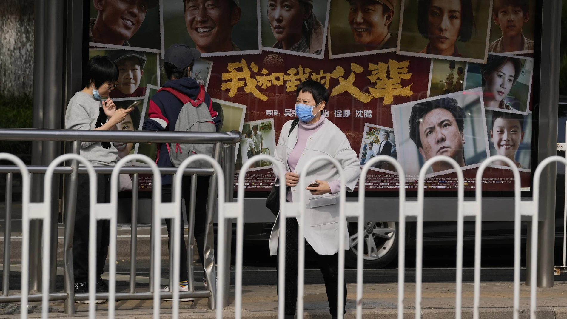 A woman wearing mask past by an advertisement for the patriotic movie "My People, My Parents" at a cinema in Beijing, China, Friday, Oct. 8, 2021. China saw a major dip in travel over the past week's National Day vacation. People staying home appeared to have chosen the cinema instead, with a patriotic Korean War film taking in more than 3.45 billion yuan ($535 million) at the box office. (AP Photo/Ng Han Guan)