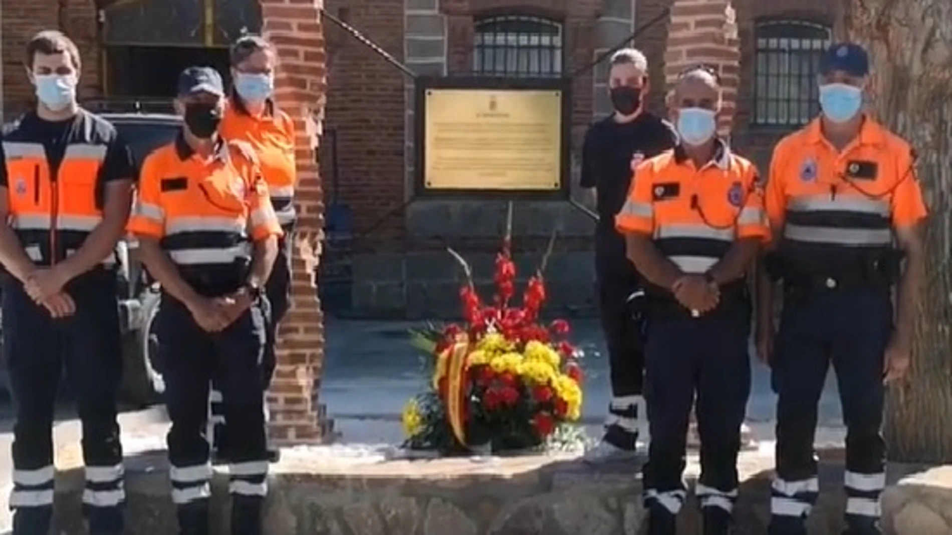 Miembros de Protección Civil de El Tiemblo, en Ávila, posan junto a la placa en recuerdo a los que dieron su vida por la covid en pandemia