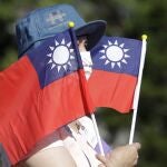 Un mujer sujeta dos banderas de Taiwán