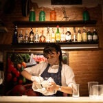 Una camarera seca unos vasos en el interior de un bar en una calle céntrica de Barcelona,
