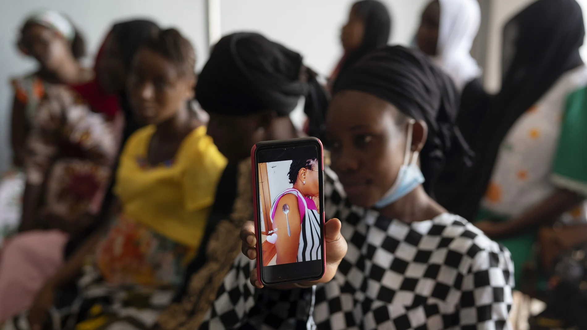 Oumie Nyassi shows a video circulating on the internet and that has been confirmed as fake news of a woman claiming she was magnetized after receiving the COVID-19 vaccine, in a doctors office at Serrekunda, Gambia hospital, Thursday Sept. 23, 2021. Nyassi, 24, said that she would get the vaccine only after delivering her baby. As health officials in Gambia and across Africa urge women to be vaccinated, they've confronted hesitancy among those of childbearing age. Although data on gender breakdown of vaccine distribution are lacking globally, experts see a growing number of women in Africa's poorest countries consistently missing out on vaccines. (AP Photo/Leo Correa)