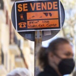Cartel anunciando una vivienda en venta en una señal de tráfico de Madrid