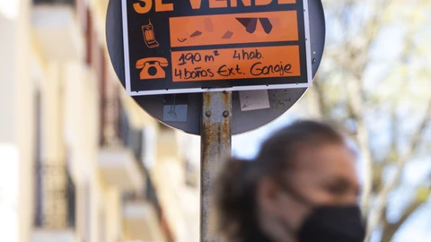 Cartel anunciando una vivienda en venta en una señal de tráfico de Madrid